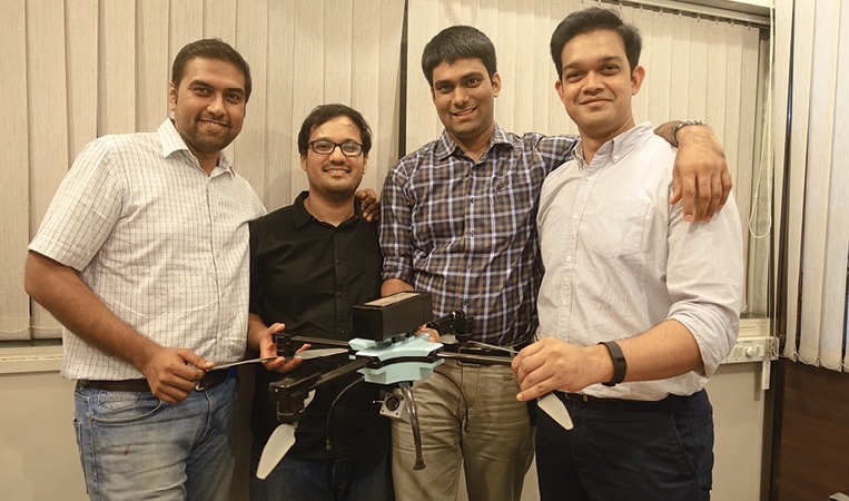 Rahul with his co-founders and one of their drones