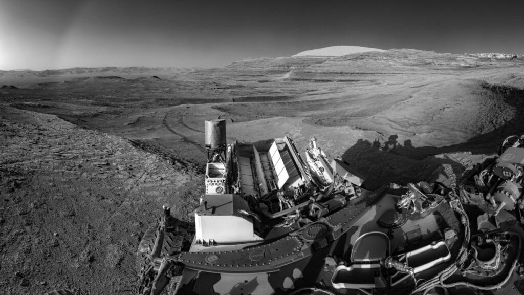 This view of tracks trailing NASA’s Curiosity was captured July 26, 2025, as the rover simultaneously relayed data to a Mars orbiter. Combining tasks like this more efficiently uses energy generated by Curiosity’s nuclear power source, seen here lined with rows of white fins at the back of the rover