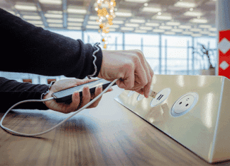 Plugging in a USB cable to charge her smartphone at a public charging station in an airport terminal