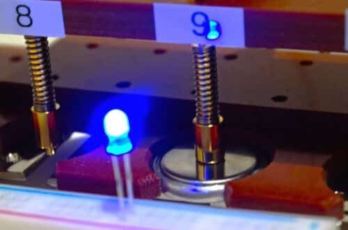 Prototype coin-cell magnesium battery with the newly developed amorphous oxide cathode powering a blue light-emitting diode (LED). Since more than 2.5 volts are required to light the LED, this demonstrates that the battery generates sufficient voltage and can deliver power to an external circuit. Credit: Tomoya Kawaguchi