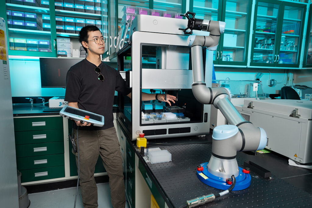 LLNL scientist Patrick Diep works with a robotic arm to automate the new protein screening method.