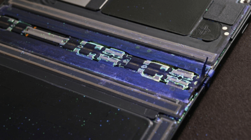 Close-up of glowing dust particles inside a foldable phone's internal hinge mechanism