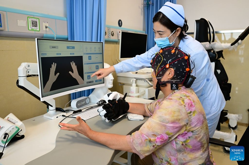 A medical worker guides a patient to use a brain-computer interface (BCI) device for hand rehabilitation at a hospital in Bengbu, east China's Anhui Province, July 17, 2026. Bengbu, a traditional industrial city, has stepped up the development of its brain-computer interface (BCI) industry in recent years. By strengthening collaboration among industry, research institutes and medical institutions, Bengbu has built an innovation ecosystem that supports both BCI research and clinical application, aiming to become an emerging BCI innovation hub in the Yangtze River Delta region. Photo: Xinhua