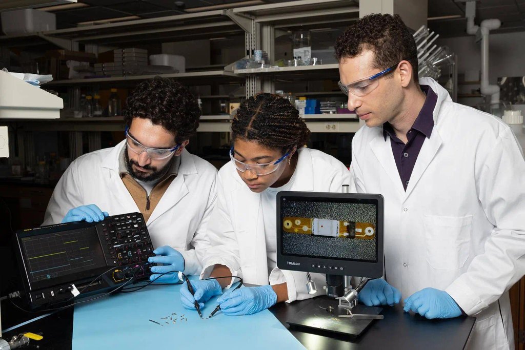 Lead study author Ramy Ghanim (left) and co-author Joy Jackson test an small implantable device alongside Assistant Professor Alex Abramson. In a new Science paper, they describe a networking system that connects therapeutic implants and wearable devices by using the body’s natural conductivity to send tiny signals.