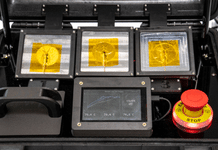 Phase-Change Heatsink Cuts Size and Weight by Half Three 3D-printed phase-change heatsink prototypes mounted in a test case, showing yellow phase-change material and a live temperature monitoring display