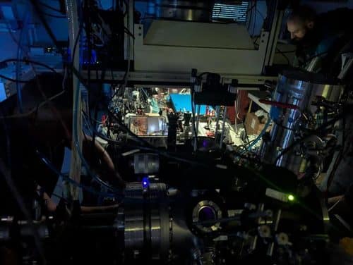 A researcher working at the nuclear clock apparatus in TU Wien’s laboratory, surrounded by lasers, optics and vacuum chamber equipment