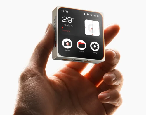 A hand holds the ESP-Mosaico Core Unit, showing its 480×480 AMOLED touchscreen with time, weather and app icons