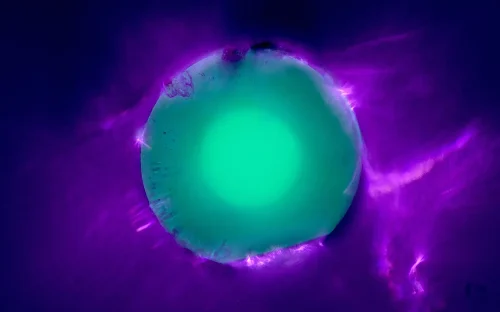 Microscopic cross-section of ZBLAN optical fibre, showing an illuminated green-blue centre surrounded by purple light.