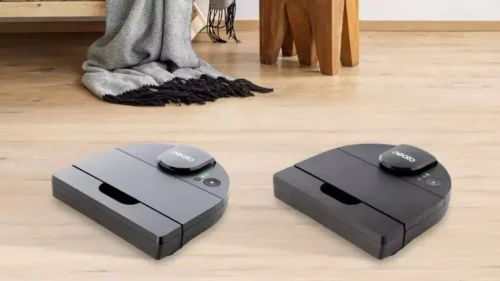 Two Neato robot vacuums, Gen3 and Gen4 models, sitting side by side on a wooden floor