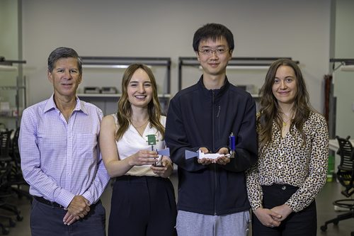Four researchers stand in a lab, with two holding the thermal-noise transmitter device and its horn antenna